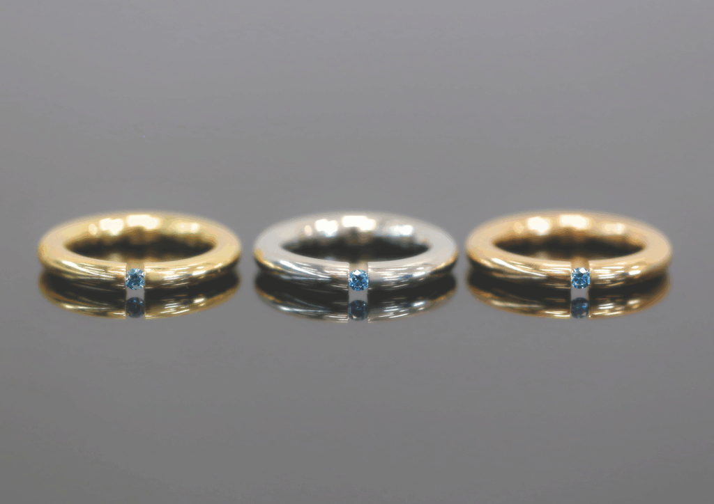 rings with 18CT Rose Gold, White Gold and Yellow Gold. Each a tension set ring with a treated blue diamond.