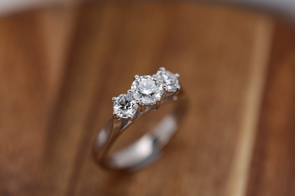 A ring, handamde in White gold, featuring three round brilliant cut diamonds in a trilogy style setting