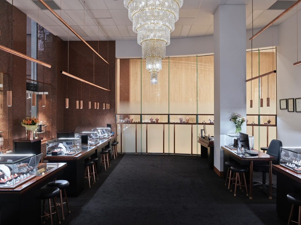 View of luxury boutique on Collins St, a chandelier, desks for client consultations and display cases of handmade jewellery