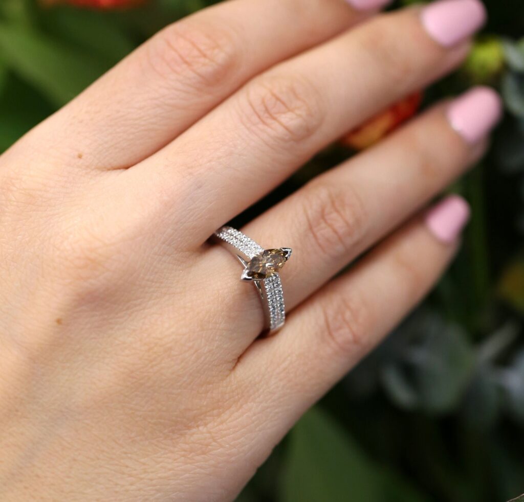 A marquise champagne diamond featured in a wide band engagement ring- with small diamonds set into the bands shoulders.