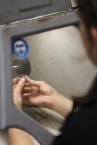 over the shoulder view of a jeweller polishing a ring on a state of the art polishing machine in an onsite jewellery workshop
