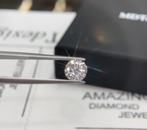 round brilliant cut white Diamond being held in tweezers to be inspected