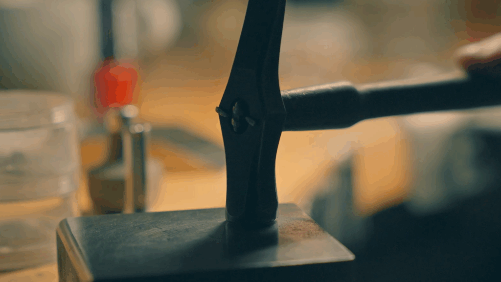 Jeweller hand-forging precious metal on an anvil using traditional hammer techniques in a Melbourne jewellery workshop