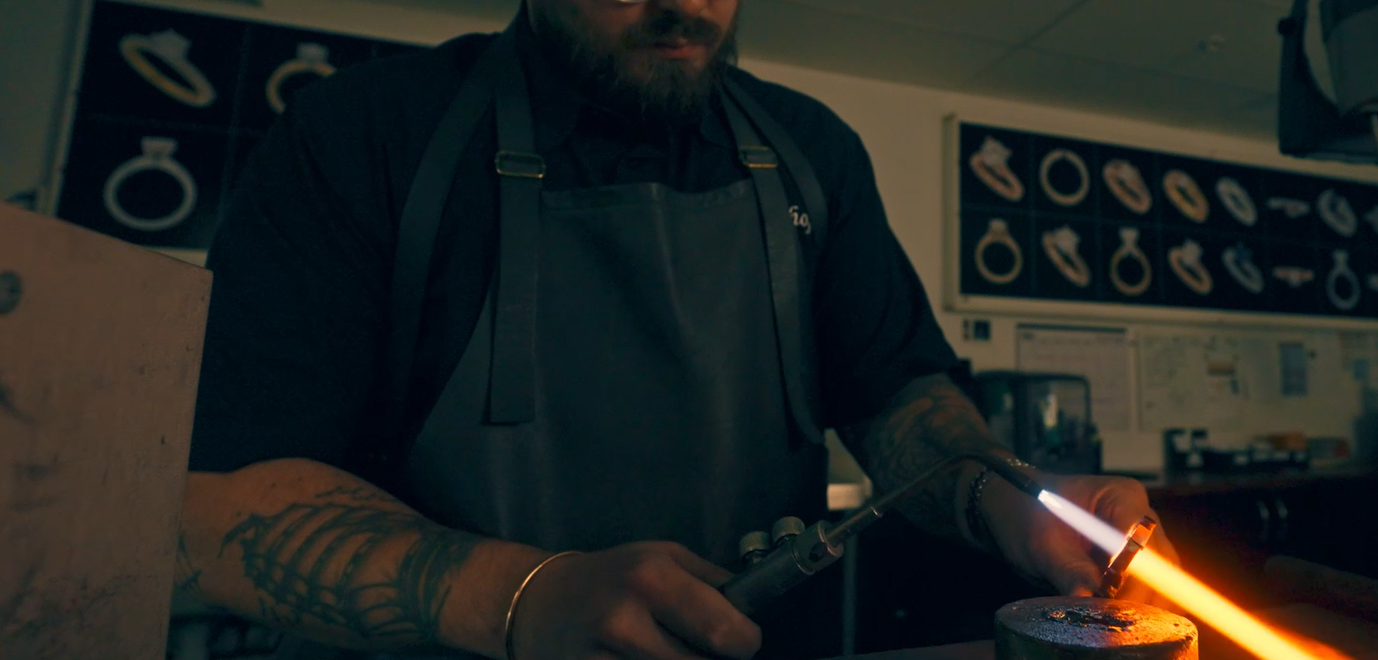 Master jeweller heating and shaping precious metal with a torch during the handmade jewellery making process in a Melbourne workshop.