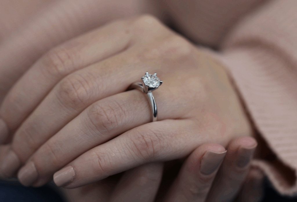 Hand wearing a handmade platinum solitaire engagement ring featuring a round brilliant cut diamond in a classic claw setting by MDT DESIGN Melbourne.