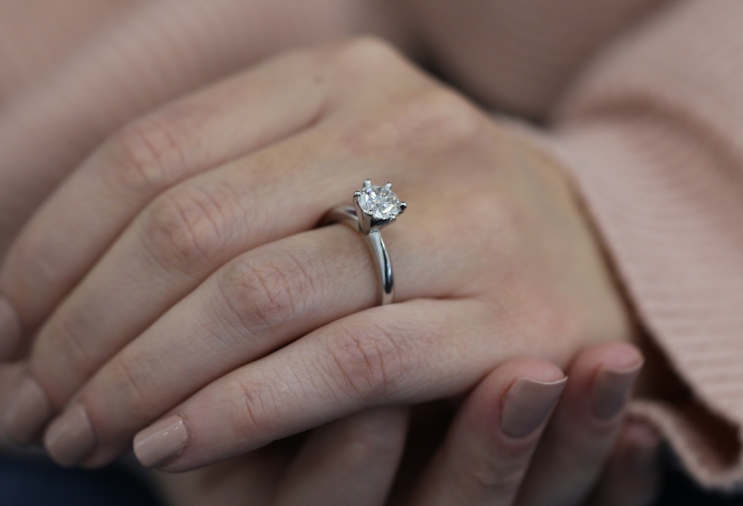 Hand wearing a handmade platinum solitaire engagement ring featuring a round brilliant cut diamond in a classic claw setting by MDT DESIGN Melbourne.