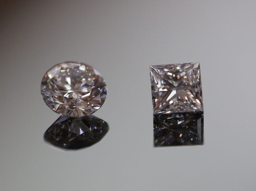 two loose diamonds, a round brilliant cut and a princess cut diamond. Both natural diamonds