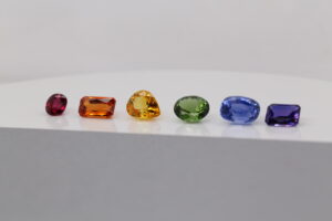 Rainbow gemstones representing pride colours arranged in a row including red, orange, yellow, green, blue and purple gemstones.