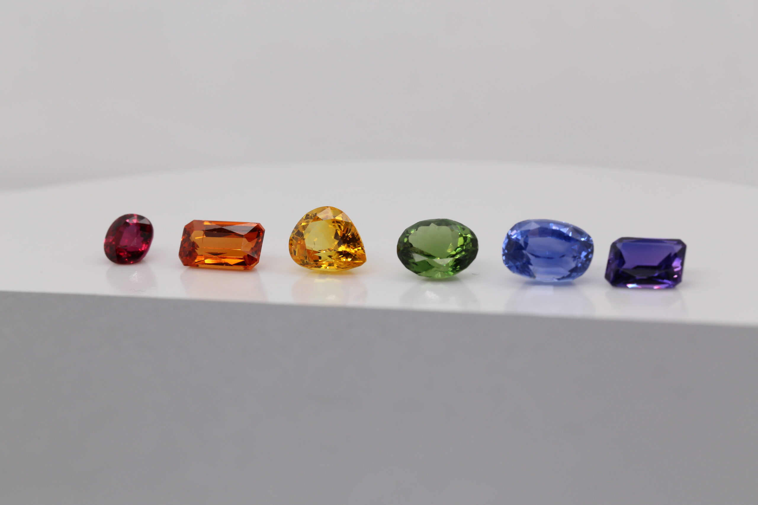 Rainbow gemstones representing pride colours arranged in a row including red, orange, yellow, green, blue and purple gemstones.