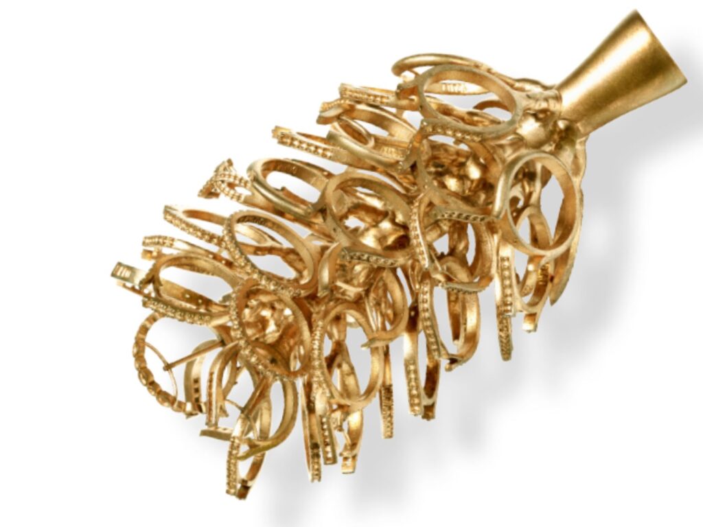 Gold casting tree displaying multiple unfinished ring settings attached to a central sprue, showing the pre-casting stage of handmade jewellery production.