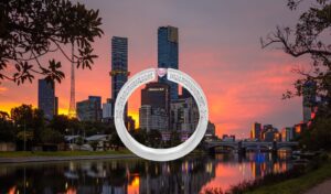 Tension set engagement ring with a pink diamond shown in side view against the Melbourne skyline and Yarra River at sunset.