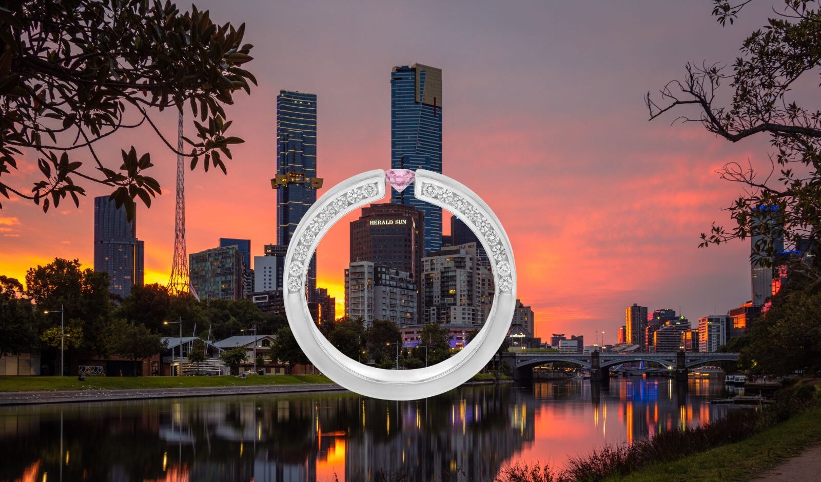 Tension set engagement ring with a pink diamond shown in side view against the Melbourne skyline and Yarra River at sunset.