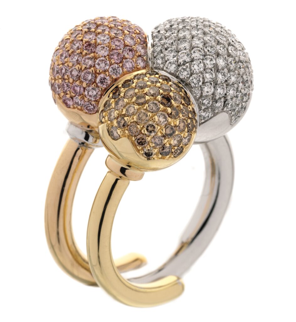 This extraordinary piece is crafted from a harmonious blend of 18ct white, yellow, and rose gold, symbolizing the unity of three distinct elements. The ring is adorned with 86 Australian Argyle pink diamonds (4P), totalling 0.53ct, along with 41 rich C5 champagne diamonds totalling 0.53ct, and 110 dazzling white round brilliant diamonds (GVS2), adding a further 1.10ct of sparkle. This award-winning design is a stunning celebration of colour, craftsmanship, and artistry.