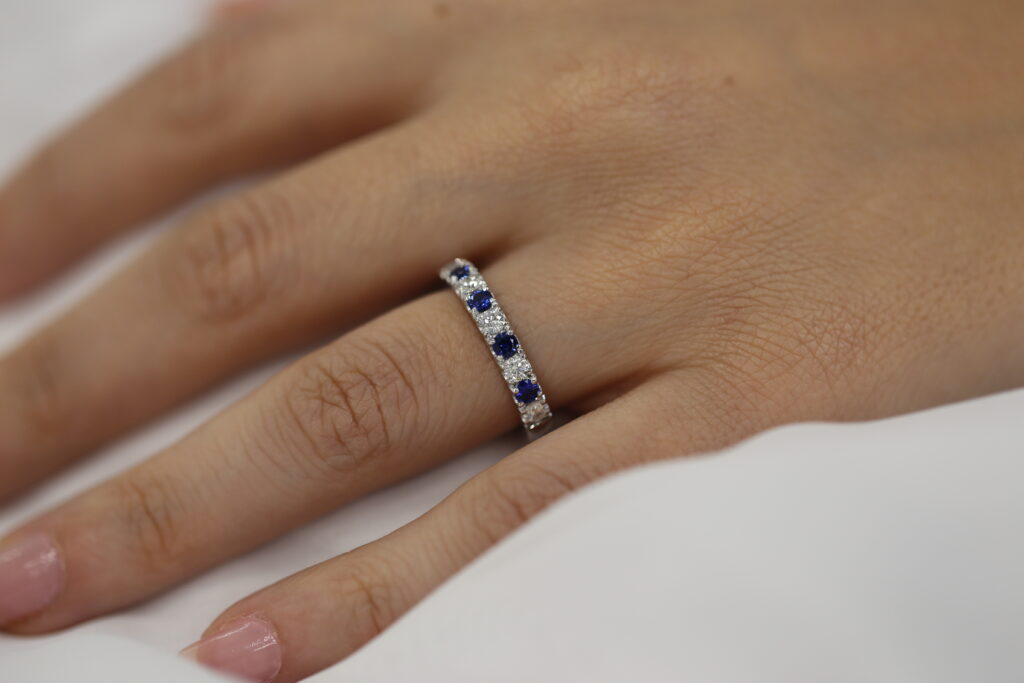 hand wearing diamond and sapphire eternity ring in white gold with alternating blue sapphires and diamonds
