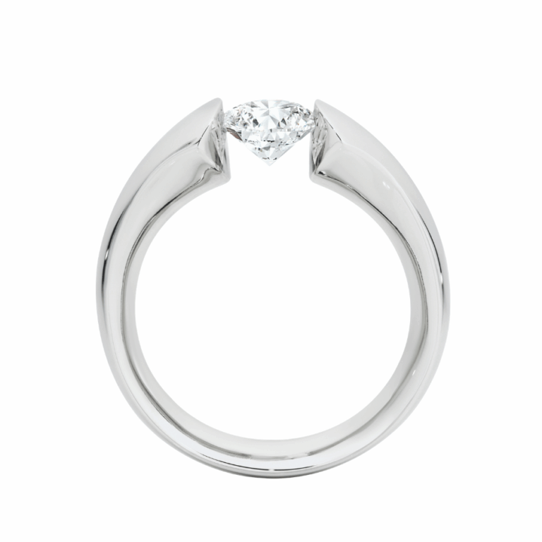 Modern tension set engagement ring featuring a round brilliant diamond suspended between polished white metal shoulders, handmade in Melbourne.