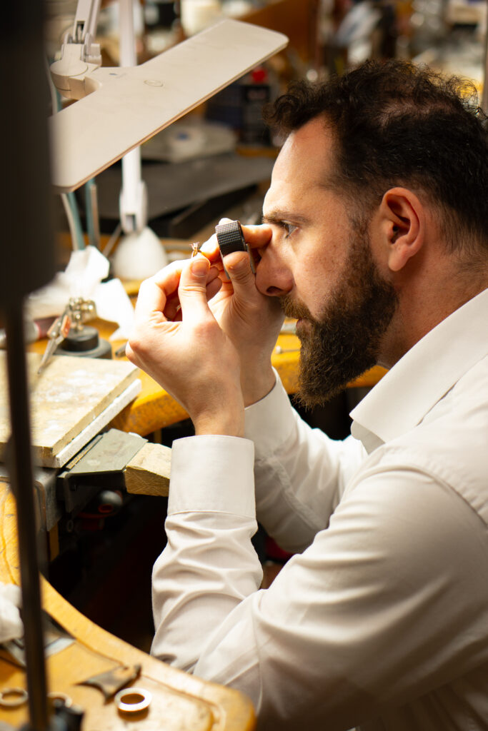 MDT DESIGN jeweller Kosta Theochari inspecting a handmade ring under magnification at the jeweller’s bench in the Melbourne workshop.