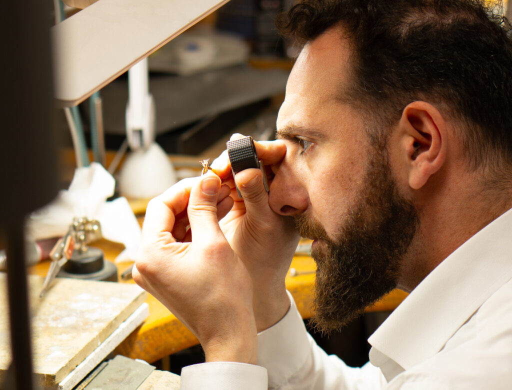 MDT DESIGN jeweller Kosta Theochari inspecting a handmade ring under magnification at the jeweller’s bench in the Melbourne workshop.