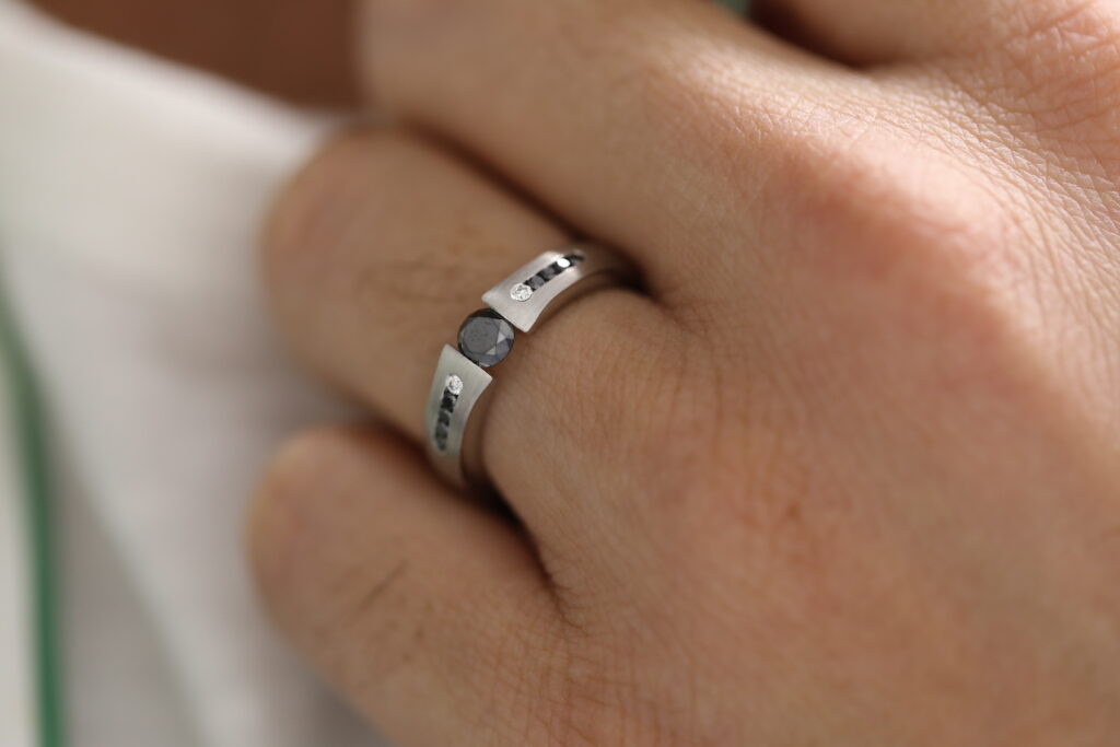 Men’s tension set ring featuring a central black diamond with contrasting black and white diamonds, individually handmade by MDT DESIGN in Melbourne.
