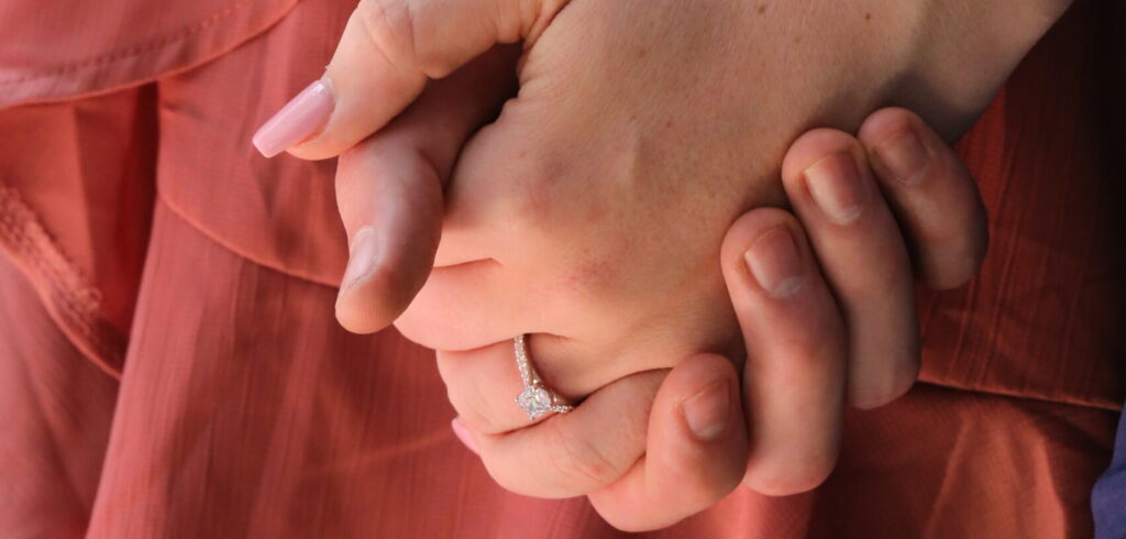 Family members holding hands while wearing diamond and wedding rings, representing the sentimental jewellery and heirlooms passed between generations.