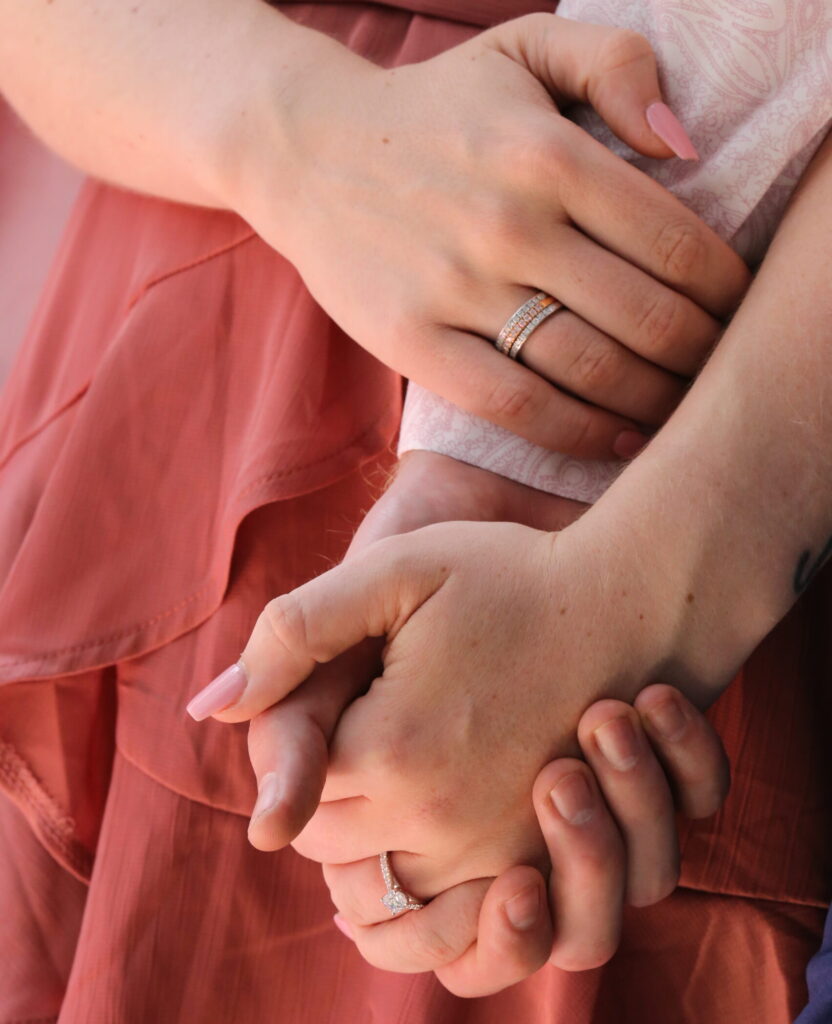 Newly engaged couple holding hands with a diamond engagement ring visible after a marriage proposal.