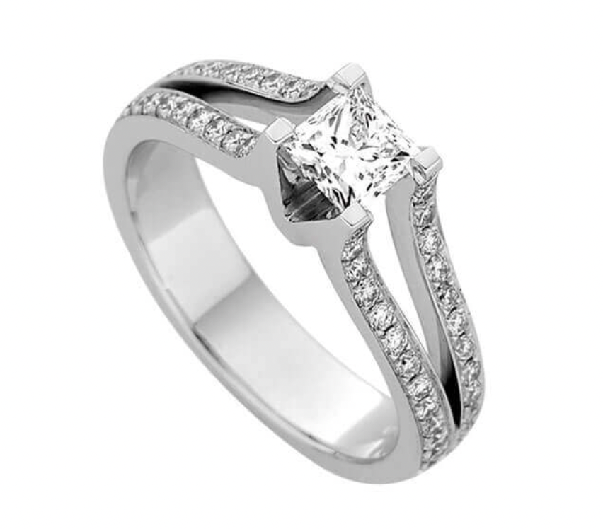 Designed for those who love modern elegance, the White Gold Princess Cut Diamond Ring C960 is a dazzling masterpiece. Handmade in 18ct white gold, this exquisite ring features a 0.60ct princess cut diamond, GIA-certified with F colour and VS2 clarity, held securely in a four-claw setting. The split band design is adorned with 54 round brilliant cut diamonds, totalling 0.43ct in F/G colour and VS clarity, meticulously grain-set for added sparkle. A striking balance of contemporary style and timeless brilliance, this ring is a radiant symbol of love.